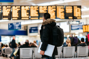 Mann mit Comuter im Flughafen vor Abflug Anzeige